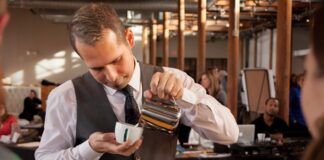 Başarılı Bir Baristanın Özellikleri Nelerdir? Kahve kültürünün hızla gelişmesiyle birlikte barista mesleği de son yılların en çok ilgi gören profesyonel alanlarından biri haline geldi. Günümüzde bir barista, yalnızca kahve hazırlayan kişi olarak görülmüyor. Aynı zamanda kaliteli hizmet sunan, kahve bilgisine hâkim olan, müşteri deneyimini geliştiren ve işletmenin marka değerine katkı sağlayan önemli bir profesyonel olarak değerlendiriliyor. Konulu bir haber görseli.