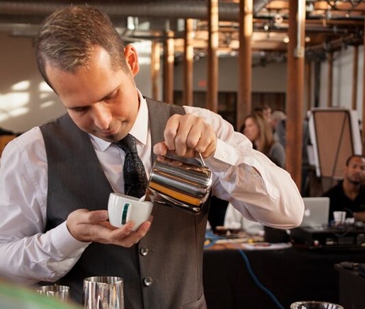 Başarılı Bir Baristanın Özellikleri Nelerdir? Kahve kültürünün hızla gelişmesiyle birlikte barista mesleği de son yılların en çok ilgi gören profesyonel alanlarından biri haline geldi. Günümüzde bir barista, yalnızca kahve hazırlayan kişi olarak görülmüyor. Aynı zamanda kaliteli hizmet sunan, kahve bilgisine hâkim olan, müşteri deneyimini geliştiren ve işletmenin marka değerine katkı sağlayan önemli bir profesyonel olarak değerlendiriliyor. Konulu bir haber görseli.